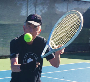 Player in black baseball cap hitting tennis ball