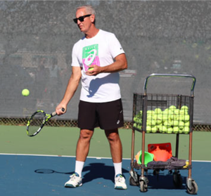 Trainer in black shorts lobbing tennis balls